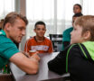 Speler van voetbalclub FC Groningen zit aan tafel en gaat vrijwillig in gesprek met leerlingen over zijn beroep.